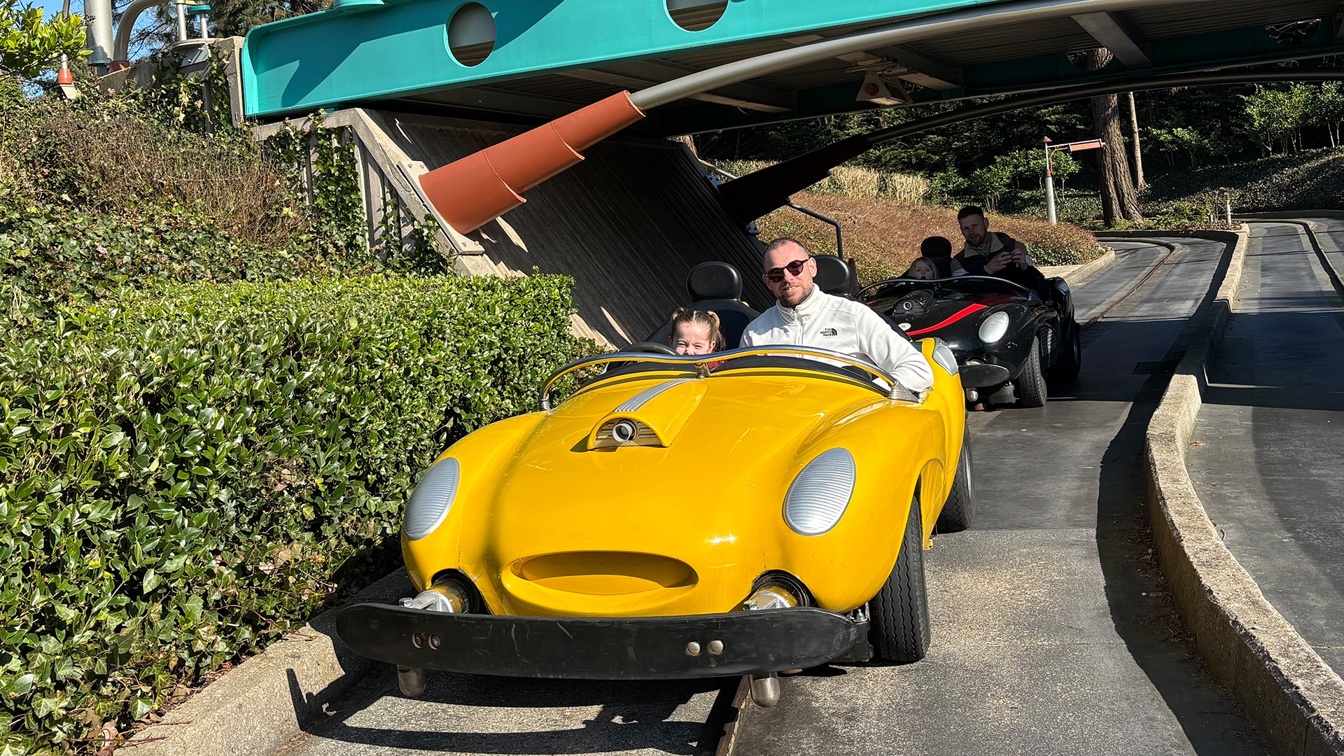 Vader Leon en dochter Lola rijden samen in een gele wagen van de attractie Autopia in Disneyland.